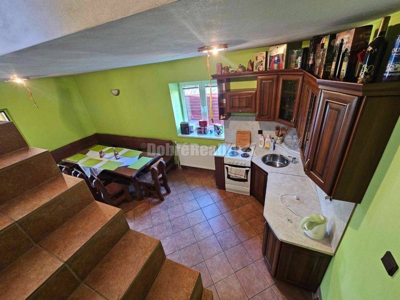 A kitchen in a family house with a staircase, wooden furniture, and green walls.
