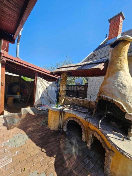 A family house in Malá Lehota with a brick fireplace in the yard.