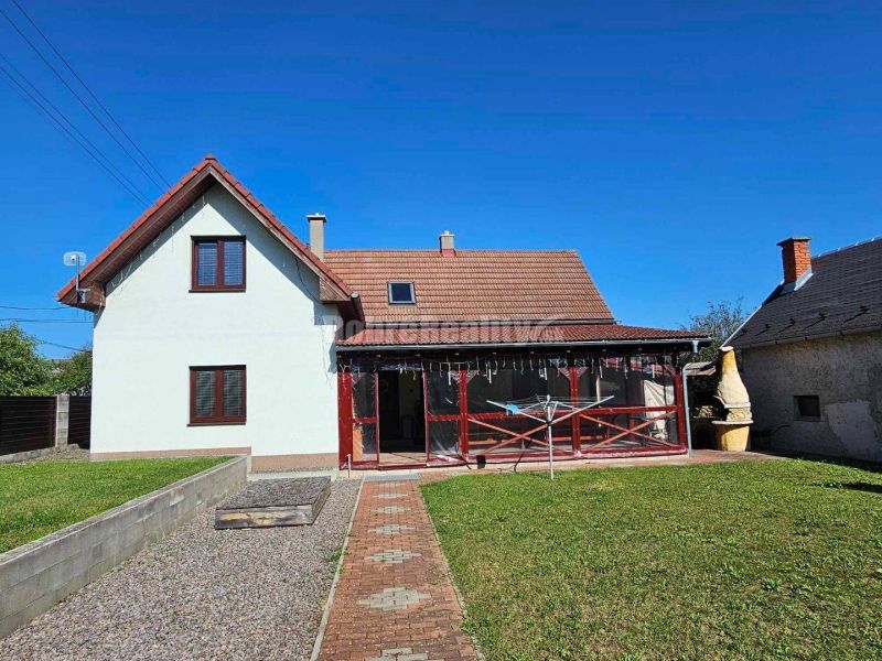 A family house in Malá Lehota with a veranda and a garden under the blue sky.