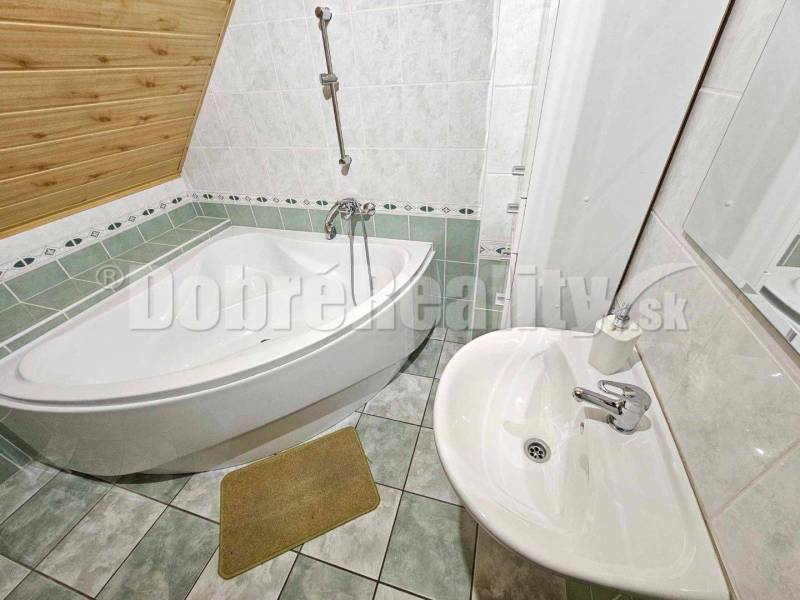 A bathroom in a family house with a sloped roof, a corner bathtub, and a sink.
