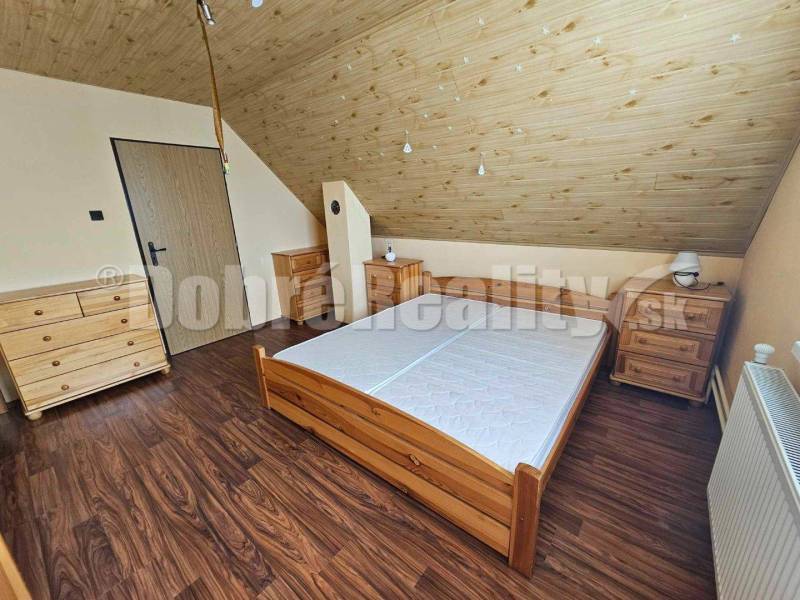An attic bedroom in a family house with wooden furniture and a sloped ceiling.
