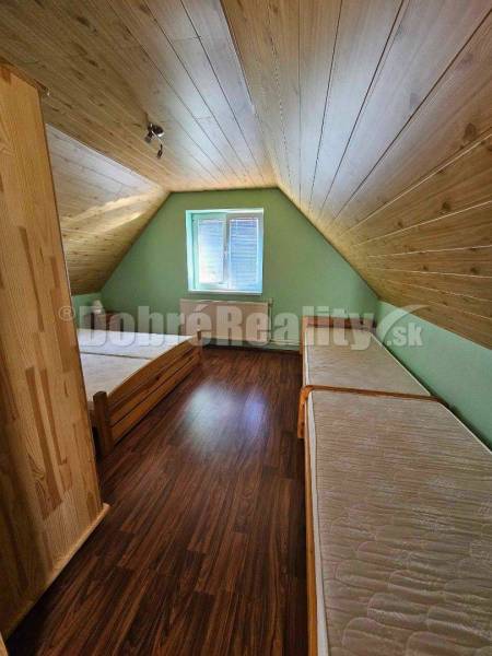 Attic room in a family house with a wooden ceiling and two beds.