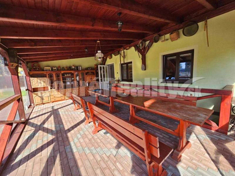 Covered terrace with wooden seating and cabinets in a family house.
