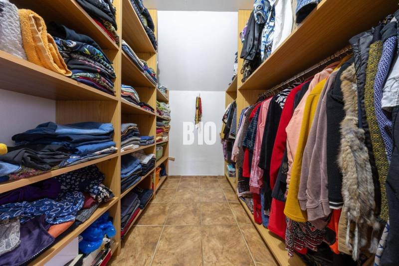 A wardrobe in a family house with shelves full of clothes and coat hangers.