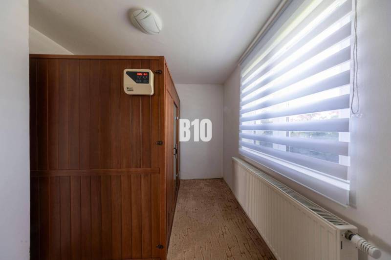 Interior of a family house with a wooden sauna and a large window with blinds.