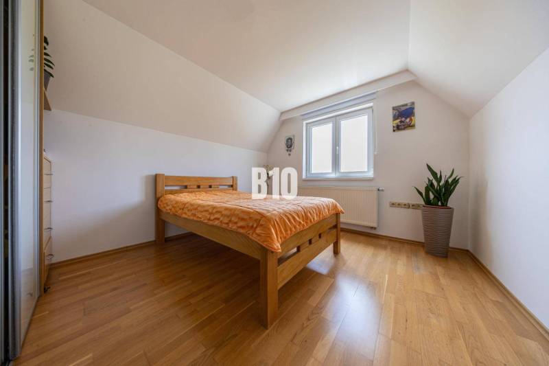 A bedroom in a family house with a sloped ceiling and a wooden bed.