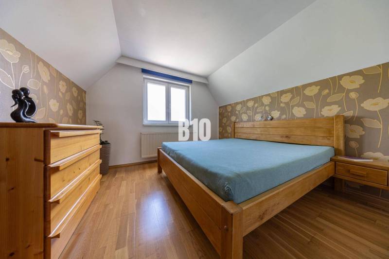 Bedroom with wooden furniture in a family house, floral wallpaper, wooden floor.