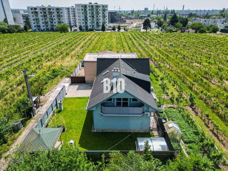 A family house in Bratislava - Nové Mesto surrounded by vineyards and nearby apartment buildings.