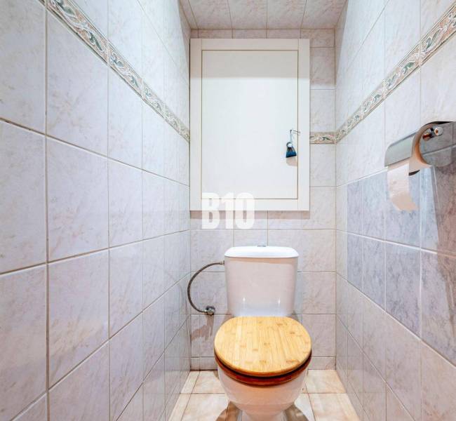 Toilet with tiles in a 3-room apartment, wooden seat, paper holder.