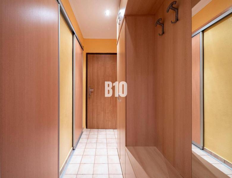 A hallway with built-in wooden wardrobes in a 3-room apartment.