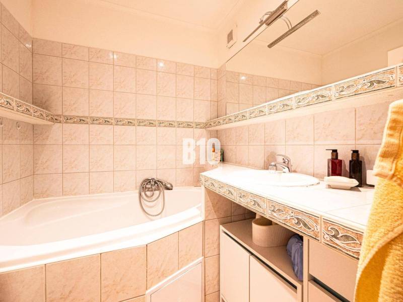 A bathroom with a bathtub and a sink in a 3-room apartment, decorated with ceramic tiles.