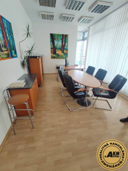 Offices with a round table and chairs, a painting hangs on the wall.
