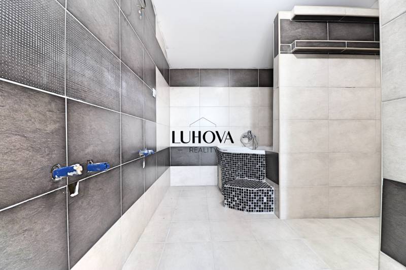 A bathroom in a family house with dark and light tiles, unfinished installation.