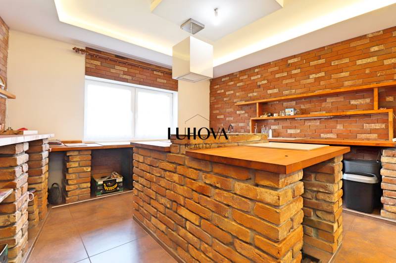 A kitchen in a family house with brick walls and a wooden counter.