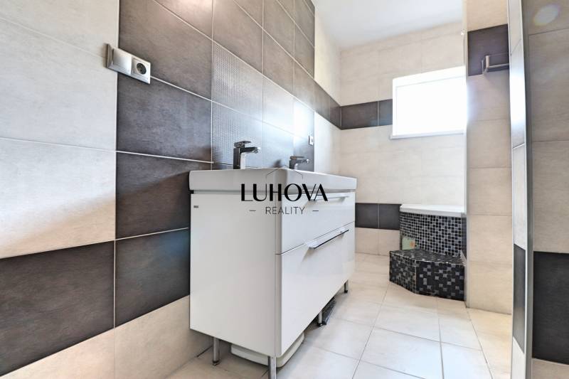 A bathroom in a family house with light tiles and a double sink.