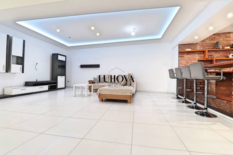 Interior of a family house with furnishings, a sofa, a bar counter, and stools.