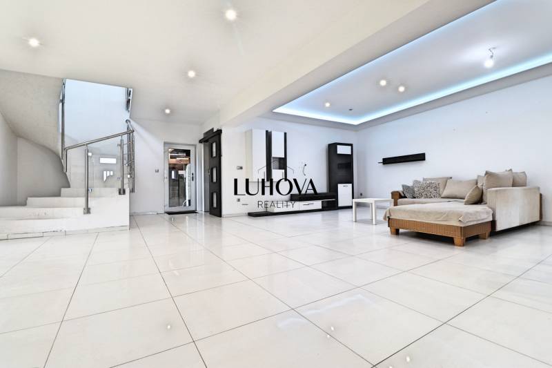 Living room with a sofa and staircase in a family house, light tiles, light walls.