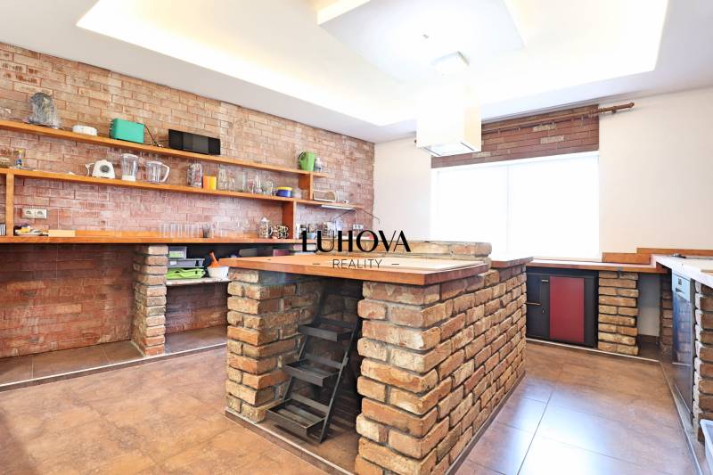 A kitchen in a family house with brick details and wooden shelves.