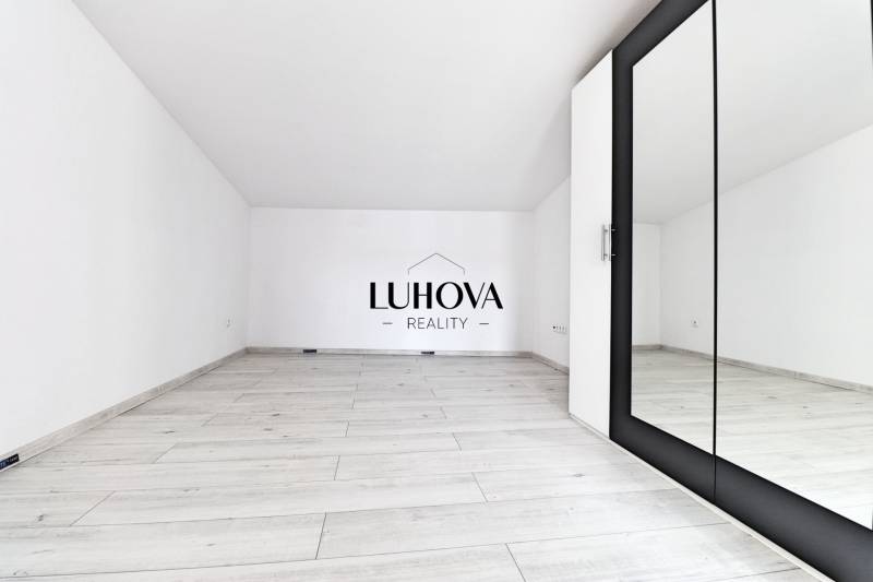 A spacious, white room with a mirror and a floor in a family house.