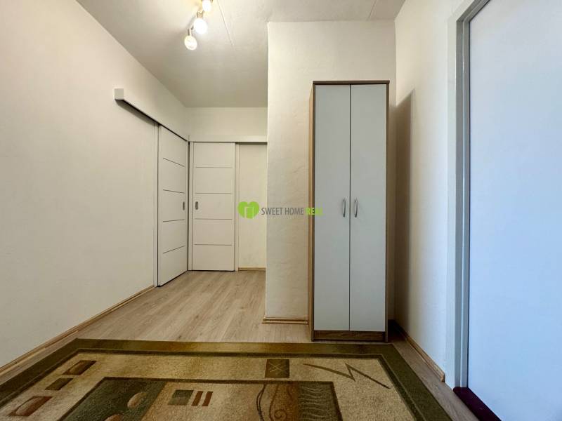 Hallway in a 3-room apartment with a carpet, a wardrobe, and sliding doors.