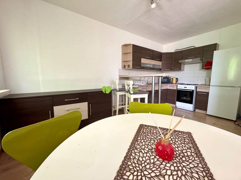 A kitchen with a stove and a dining table in a 3-room apartment.