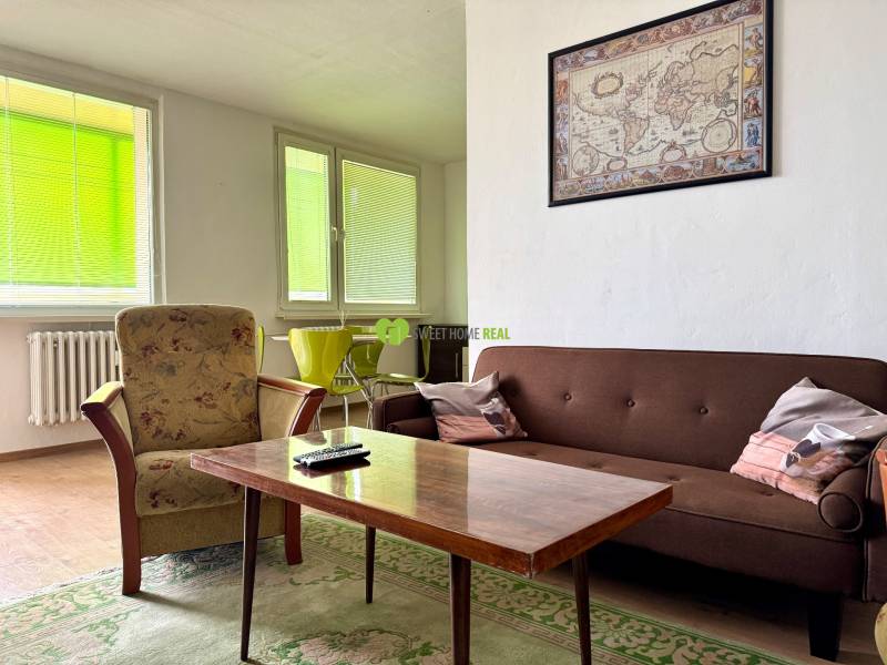 Living room with a sofa, an armchair, a table, and a map on the wall in a 3-room apartment.
