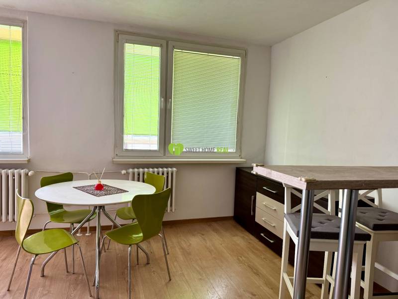 Dining area with a table and green chairs in a 3-room apartment.