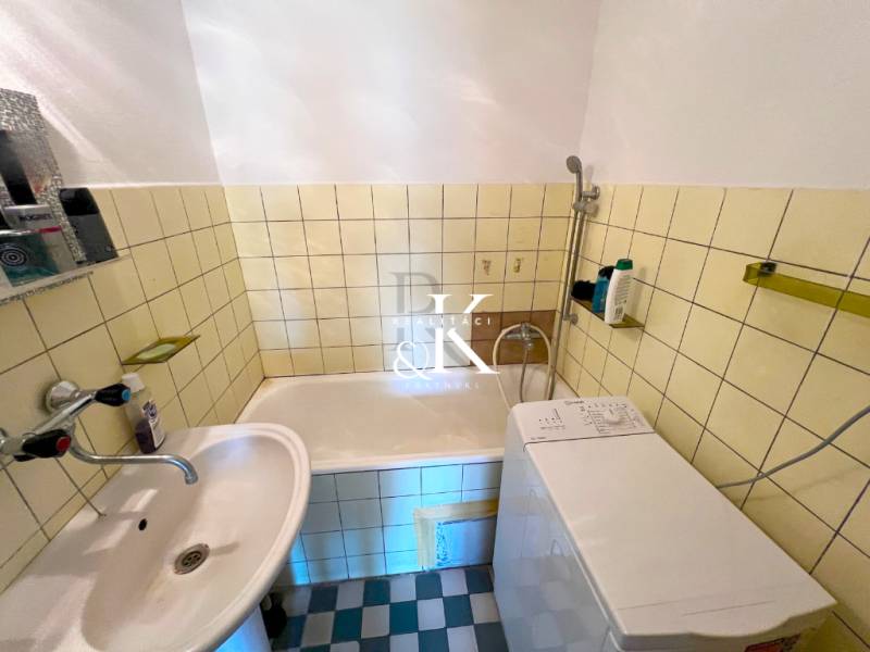 Bathroom with a bathtub, sink, and washing machine in a 2-room apartment.
