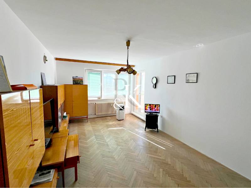 Living room in a two-room apartment with wooden furniture and a TV on a stand.