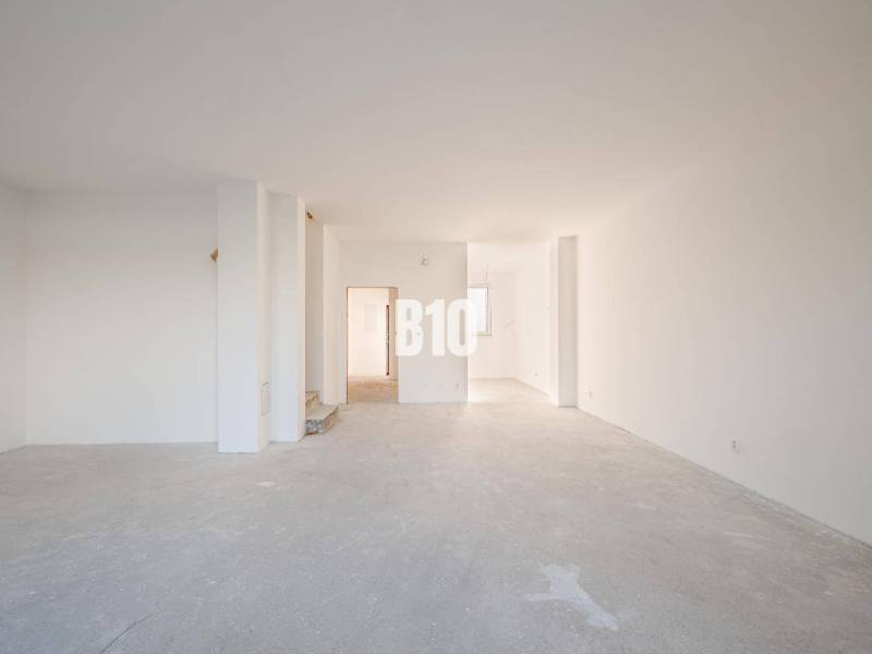 The interior of a family house with a spacious unfinished room and white walls.
