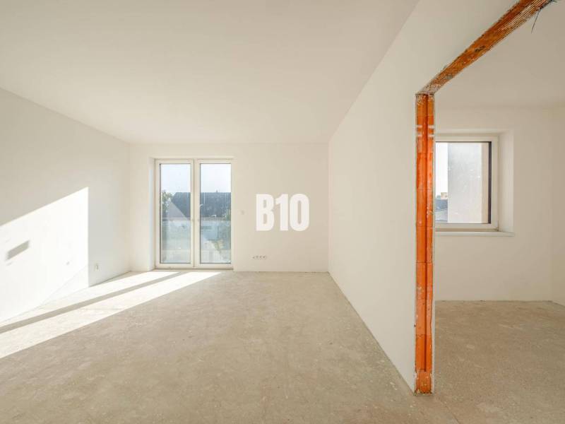 An empty interior of a family house with large plastic windows and a concrete floor.