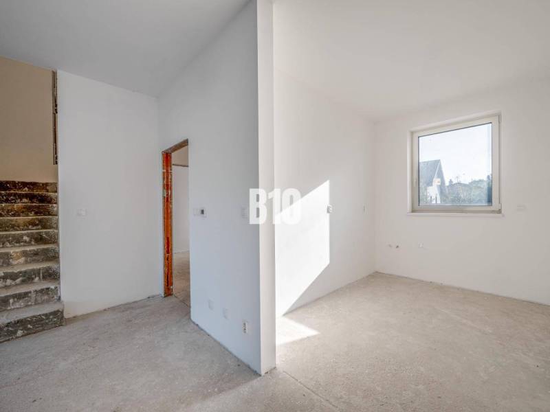 Interior of a family house with an empty room, staircase, and window without flooring.