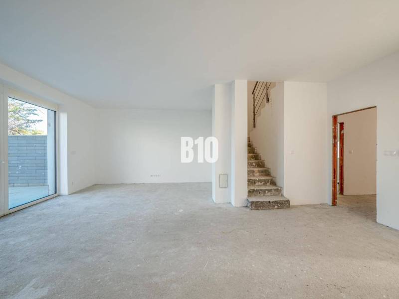 A spacious interior with an unfinished floor and a staircase in a family house.