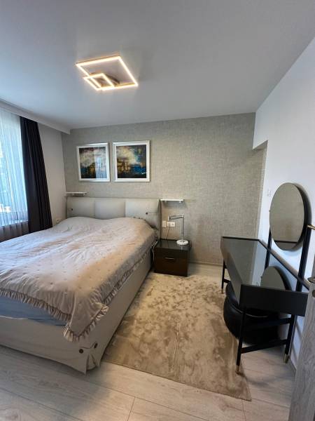 Bedroom in a family house with a bed, lamp, table, and wall decoration.