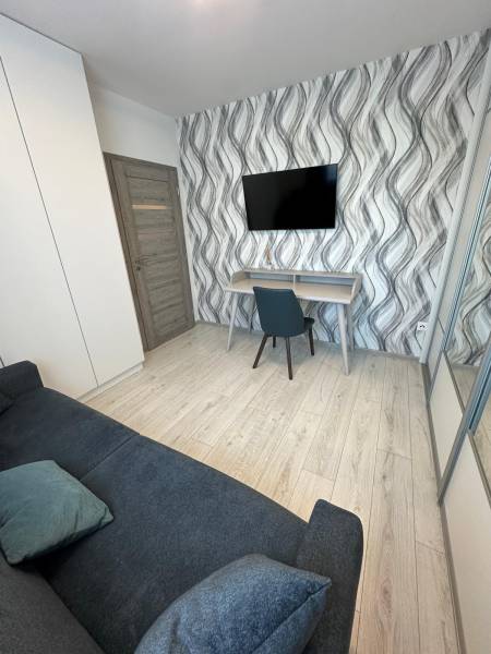 A room in a family house with wavy wallpaper, a television, a sofa, and a desk.