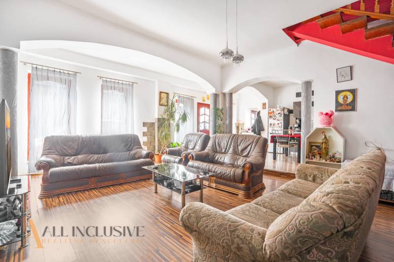 Living room with leather sofas and a wooden staircase in a family house.