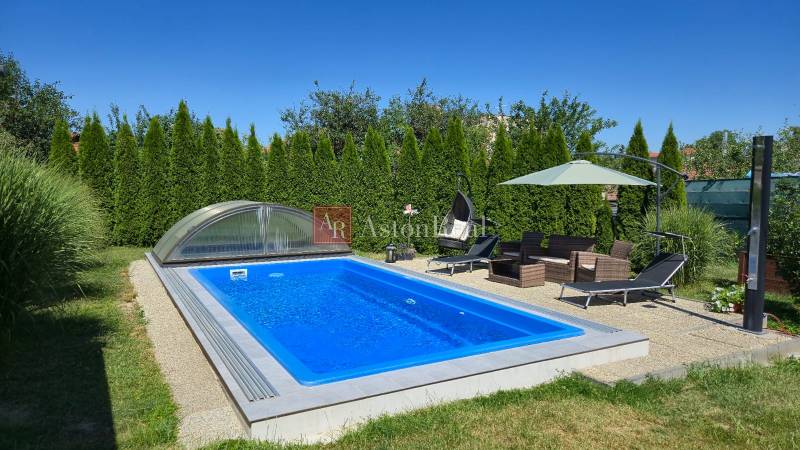 A swimming pool with a roof, garden furniture, and a sunshade at a family house in Trenčianske Jastrabie.
