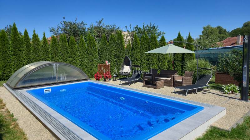 A swimming pool with a garden seating area and loungers in a family house in Trenčianske Jastrabie.