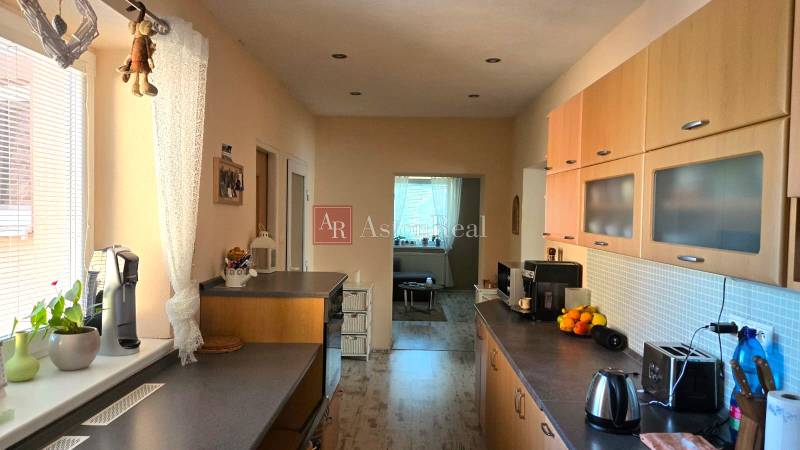 A kitchen in a family house with wooden cabinets, appliances, and a window with a view.