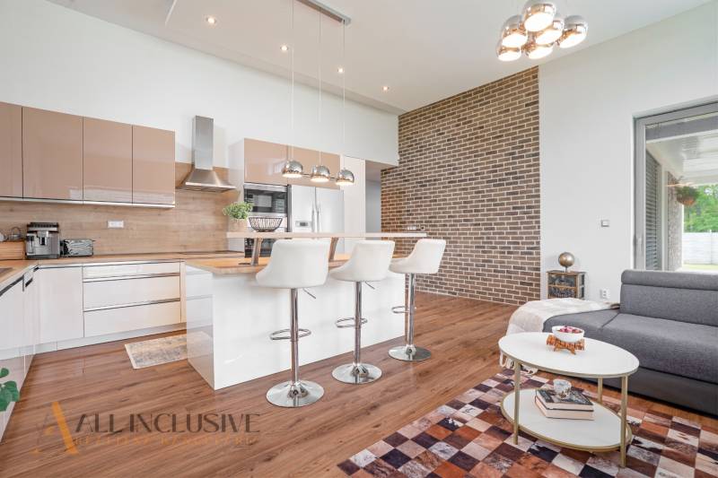 A kitchen with an island and bar stools in a family house, brick wall.