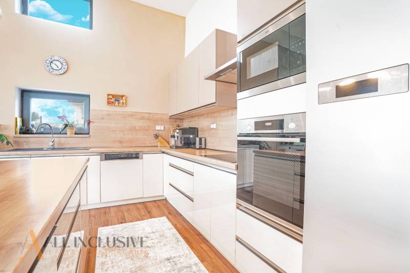 A kitchen in a family house with modern appliances and a large window.
