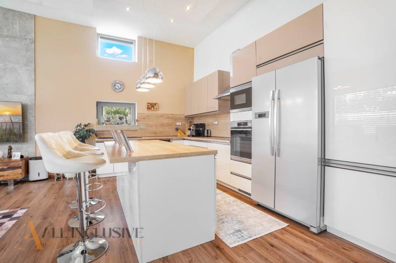 A kitchen in a family house with white cabinets, bar stools, and built-in appliances.