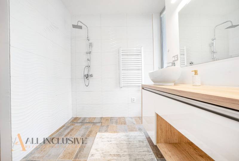 A bathroom in a family house with a sink, shower, and white tiles.