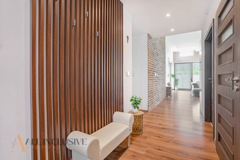 A hallway of a family house with a wooden wall, a light bench, and decorative elements.