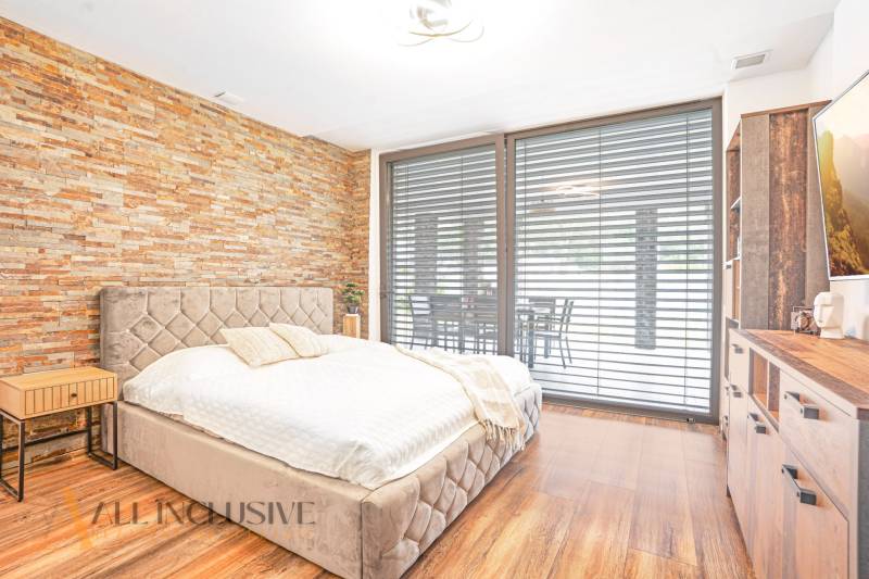 Bedroom with a stone wall, a comfortable bed, and an expansive view through the window in a family house.