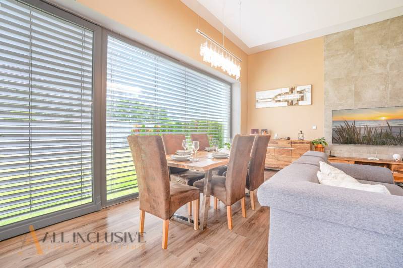 Dining area in a family house with a wooden table, chairs, and a shaded window.