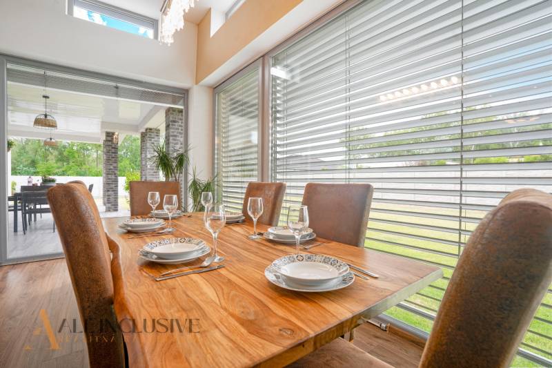 Dining room in a family house with a wooden table, set with dishes and a view of the terrace.