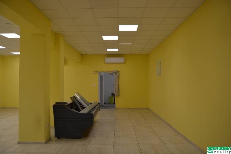 Yellow walls, tiles, and ceiling lights in commercial spaces.