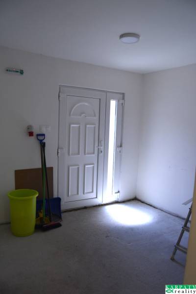 An empty room with white doors, a bucket, and cleaning supplies in commercial premises.