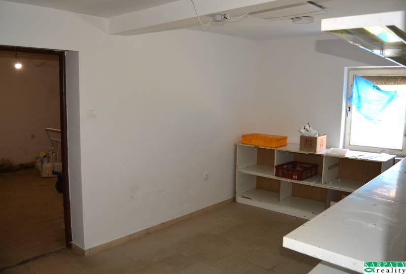 Interior of commercial spaces with shelves and a window covered with blue fabric.